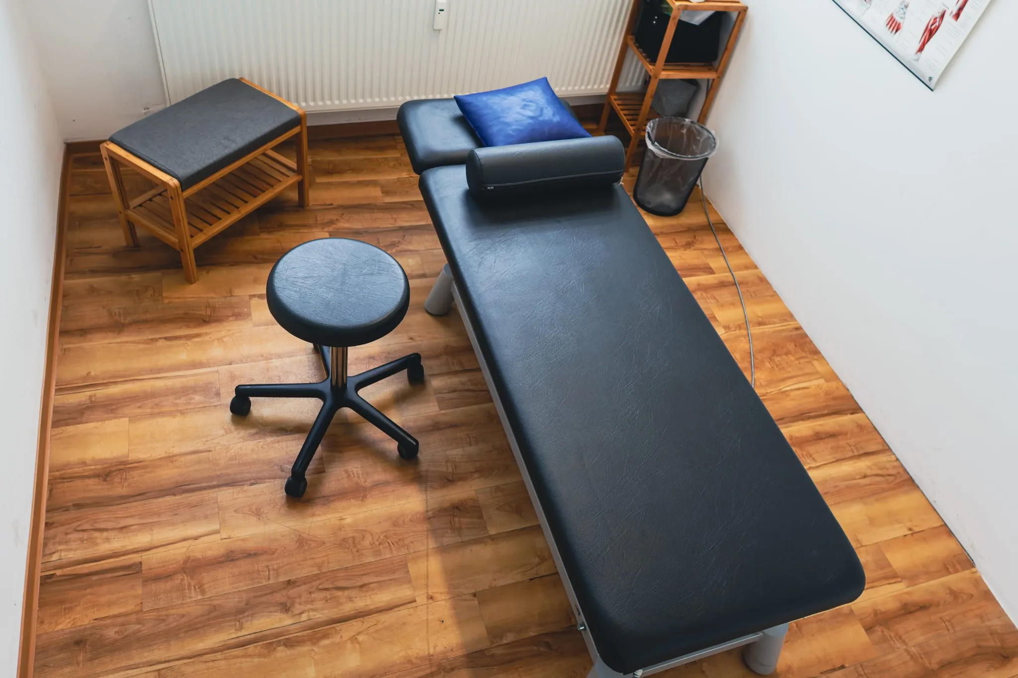 Behandlungsraum der AMILU Ergotherapie in Oberursel mit dunkler Therapieliege und Hocker